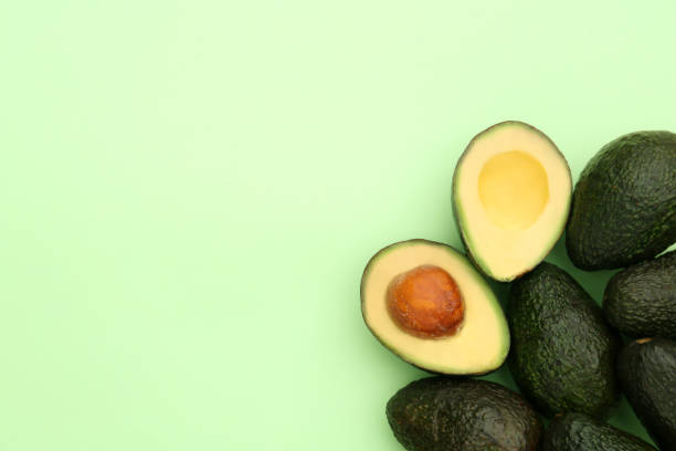 istock Tasty whole and cut avocados on light green background, flat lay. Space for text 1492484047
