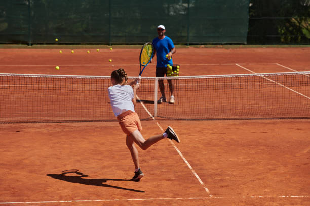 uma tenista profissional e seu treinador treinando em um dia ensolarado na quadra de tênis. treinamento e preparação de um tenista profissional - tennis coach serving playing - fotografias e filmes do acervo