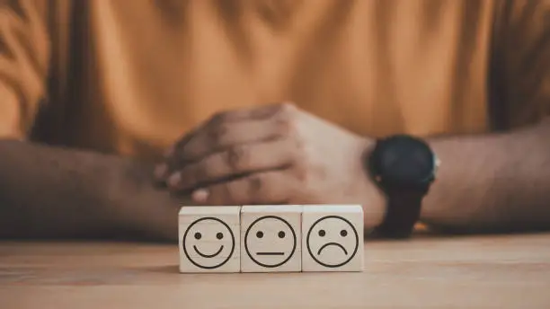 Photo of Wooden cube with smiley, normal and sad face icon.