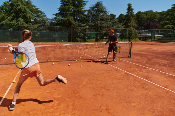 uma tenista profissional e seu treinador treinando em um dia ensolarado na quadra de tênis. treinamento e preparação de um tenista profissional - tennis coach serving playing - fotografias e filmes do acervo