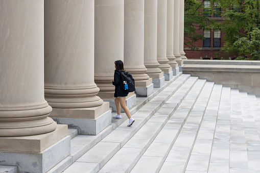 Cambridge, MA, USA - June 29, 2022: A student walks up the stairs to the main door of the Harry Elkins Widener Memorial Library, Harvard University's flagship library, in Cambridge, Massachusetts.