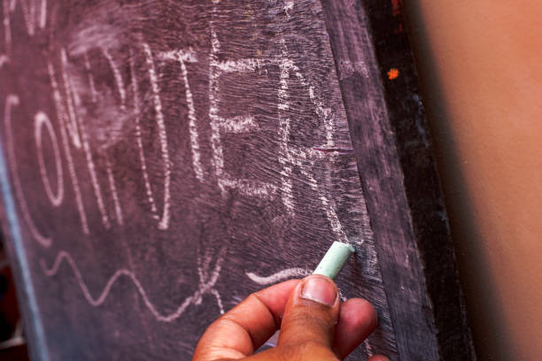 istock Male left hand writing on black board holding chalk. Teaching concept. 1492493883