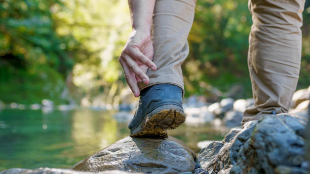 istock A man touches his foot on the riverbank in forest 1492500472