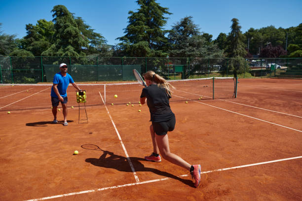 uma tenista profissional e seu treinador treinando em um dia ensolarado na quadra de tênis. treinamento e preparação de um tenista profissional - tennis coach serving playing - fotografias e filmes do acervo