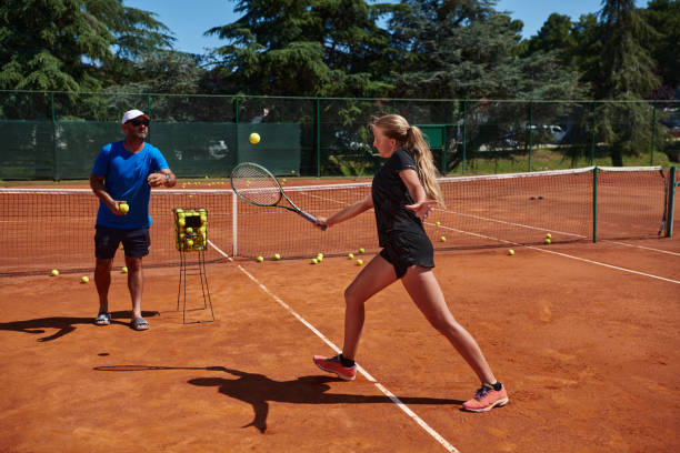 uma tenista profissional e seu treinador treinando em um dia ensolarado na quadra de tênis. treinamento e preparação de um tenista profissional - tennis coach serving playing - fotografias e filmes do acervo