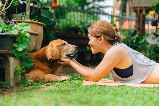 Happy woman lying on exercise mat playing with her pet dog