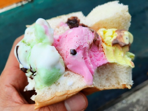 Ice cream on bread bun in hand.