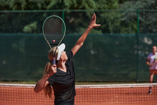 晴れた日に活気のあるテニスの試合をしている若い女の子が、現代のテニスコートでスキルと熱意を示しています。 - skill vitality agility strength ストックフォトと画像