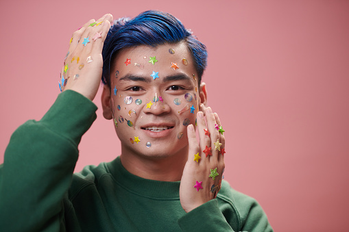 Portrait of joyful young man with stickers on face and hands