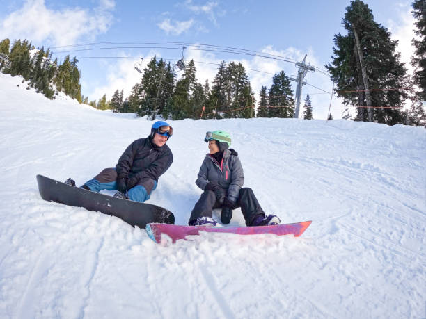 snowboarders multirraciales de parejas mayores relajándose en una pista de esquí vacía - mt seymour provincial park fotografías e imágenes de stock