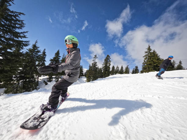 Multiracial Senior Couple Snowboarding Together on Sunny Ski Slope