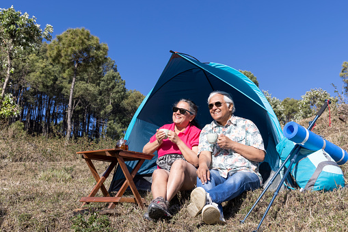 Senior couple drinking coffee and camping in nature