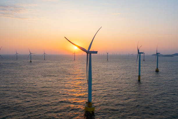 Close-up of wind turbines at sea at sunrise The mechanical beauty of a windmill turning: a close-up of an offshore wind turbine at sunrise offshore wind farm stock pictures, royalty-free photos & images