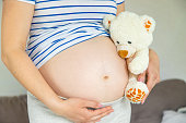 Pregnant woman and white teddy bear. Selective focus.