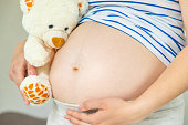 Pregnant woman and white teddy bear. Selective focus.