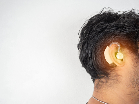 An asian man is wearing a hearing aid on white background. Space for text.