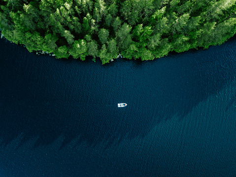 Aerial view fishing boat in blue lake and green woods in summer Finland