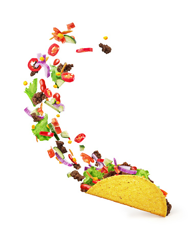 Chopped toppings flying out of a Mexican taco isolated on a white background