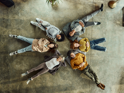 High angle view of young relaxed people lying on floor in the office. Copy space.