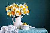 A bouquet of garden daffodils and quince on the table on a blue background. Still-life.