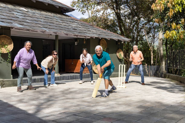 familienmitglieder spielen cricket im hinterhof. - indian culture family senior adult asian ethnicity stock-fotos und bilder