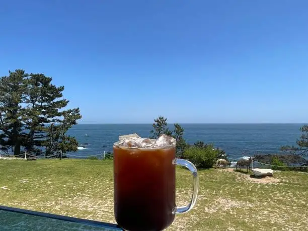 Photo of A cup of iced coffee with ocean view.