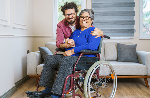 Mid adult man hugging his disabled mother at home