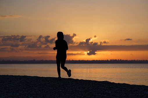 Young woman running on the beach at sunrise