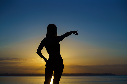 Young woman exercising on the beach at sunrise