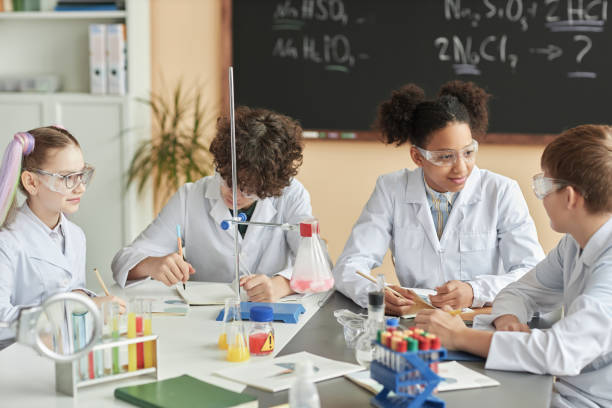istock Group of schoolchildren wearing lab coats during science experiment class 1492537623