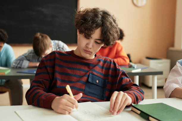 istock Teenage boy writing in notebook during school class 1492537779