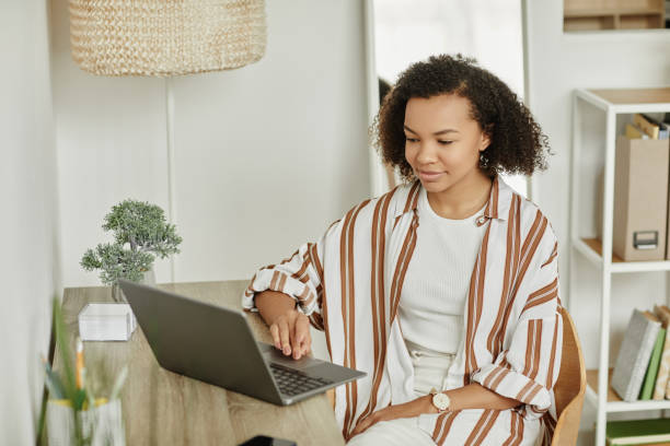 istock Black young woman using laptop at home office workplace in white 1492538454