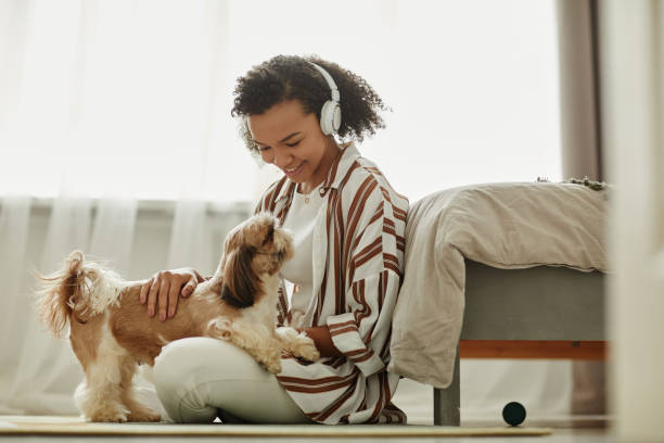 Woman playing with little dog on floor and listening to music