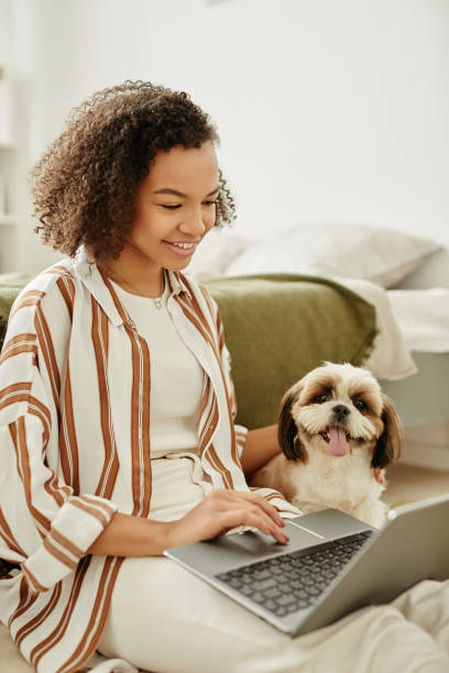 istock Smiling black girl using laptop on floor with little pet dog 1492538499