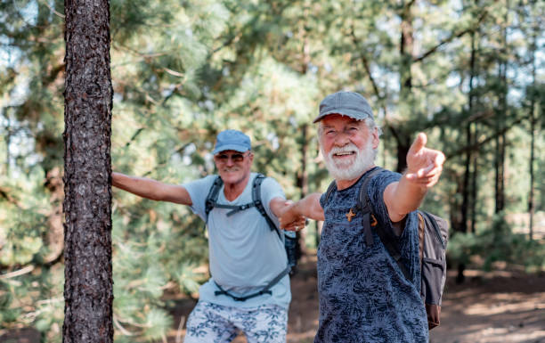istock Happy smiling couple of elderly men with hat and backpack looking in camera while enjoying mountain hike in the woods appreciating adventure and freedom, retired seniors and healthy lifestyle concept 1492539405