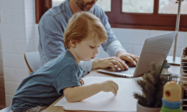 istock Father working from home office using laptop sit at table with cute little son playing nearly to disturb. 1492544538