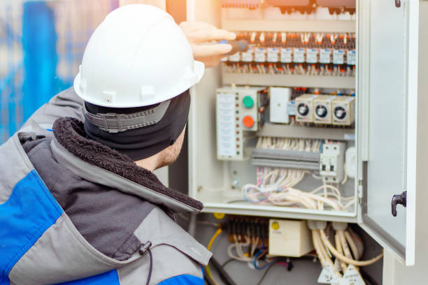 istock Professional electrician connects wires in electrical switchboard. 1492545539