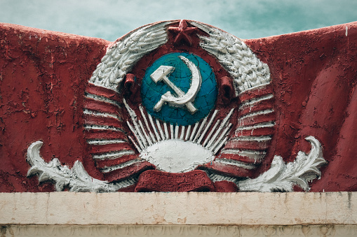 This photo features a cracked old emblem of the USSR. The emblem is a symbol of the Soviet Union that was dissolved in 1991. The emblem is a reminder of the Soviet era and its impact on the world.