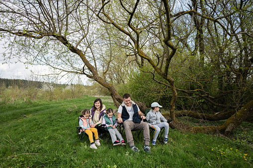 Family with three kids sitting on chairs at spring forest.