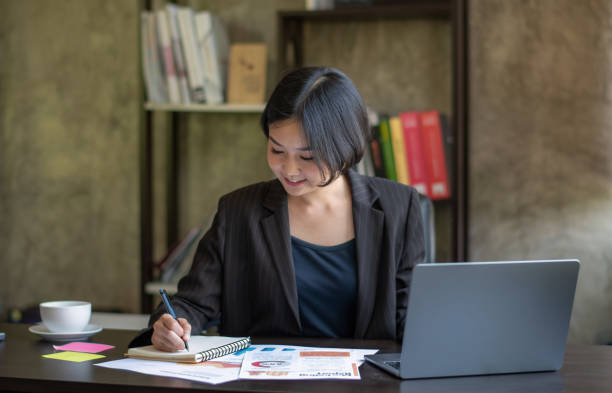 istock Asian businesswoman is working her job write information on notebook in office. 1492547823