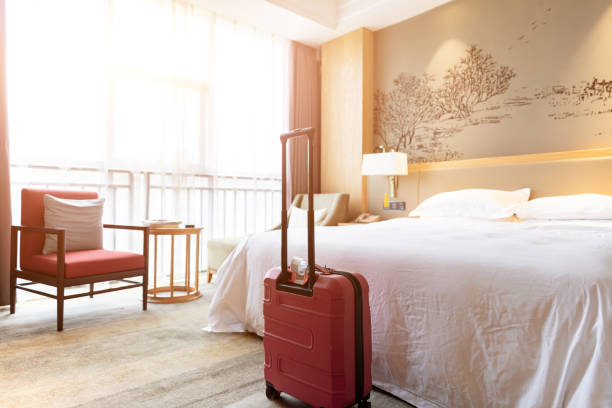 istock Hotel room with big bed sofa and red suitcase, guest just checked in 1492550700