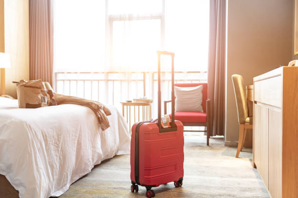 Hotel room with big bed sofa and red suitcase, guest just checked in