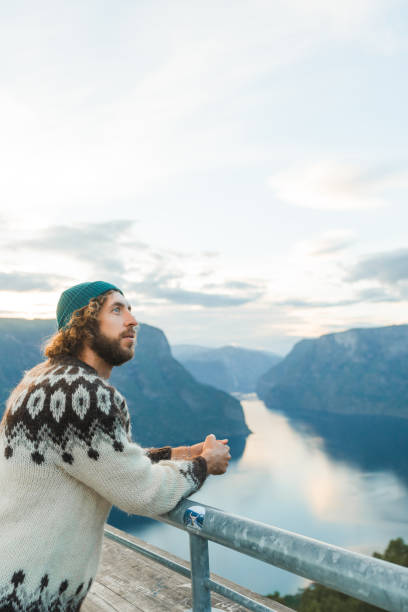 Man in knitted sweater looking at scenic view of Aurlandsfjord in Norway from Stegastein viewpoint Cheerful man in knitted sweater looking at scenic view of fjord in Norway from Stegastein viewpoint stegastein viewpoint stock pictures, royalty-free photos & images