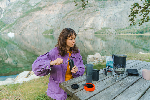 Young Caucasian woman brewing coffee in nature