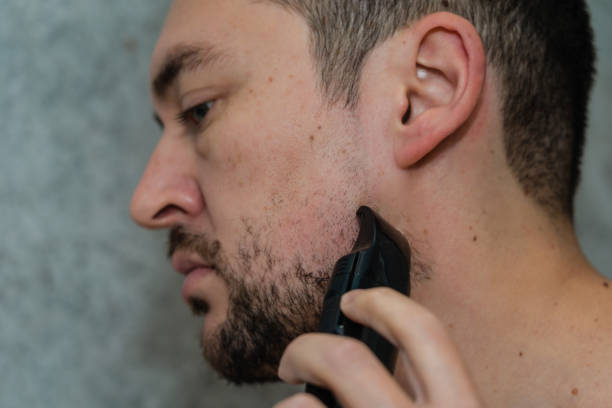 istock Handsome man shaving his beard by electric razor 1492552764