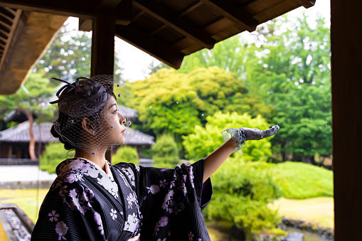 A woman gently capturing raindrops with her hand.