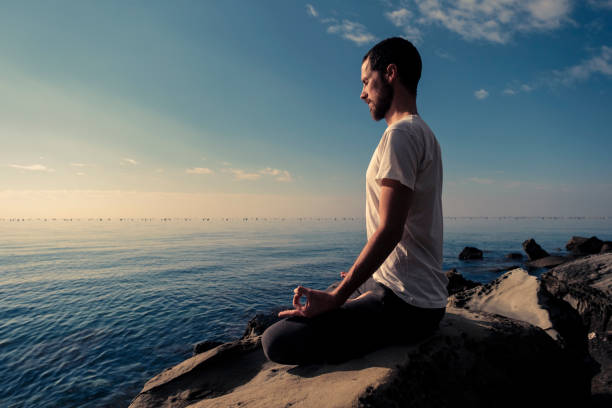 istock Attractive young man practicing yoga meditation and breathwork outdoors by the sea 1492558332