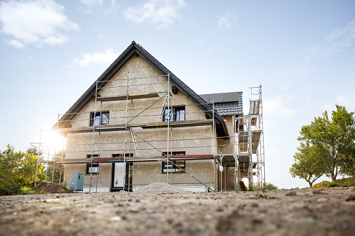 Construction site of a German single-family home at sunrise. With green trees and sunshine.