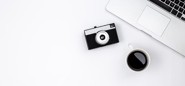 Minimalistic background with laptop, black coffee cup and retro camera, copy space.