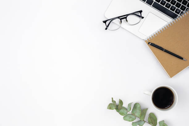 istock Flat lay white background with laptop, notepad, coffee cup and glasses. 1492558659